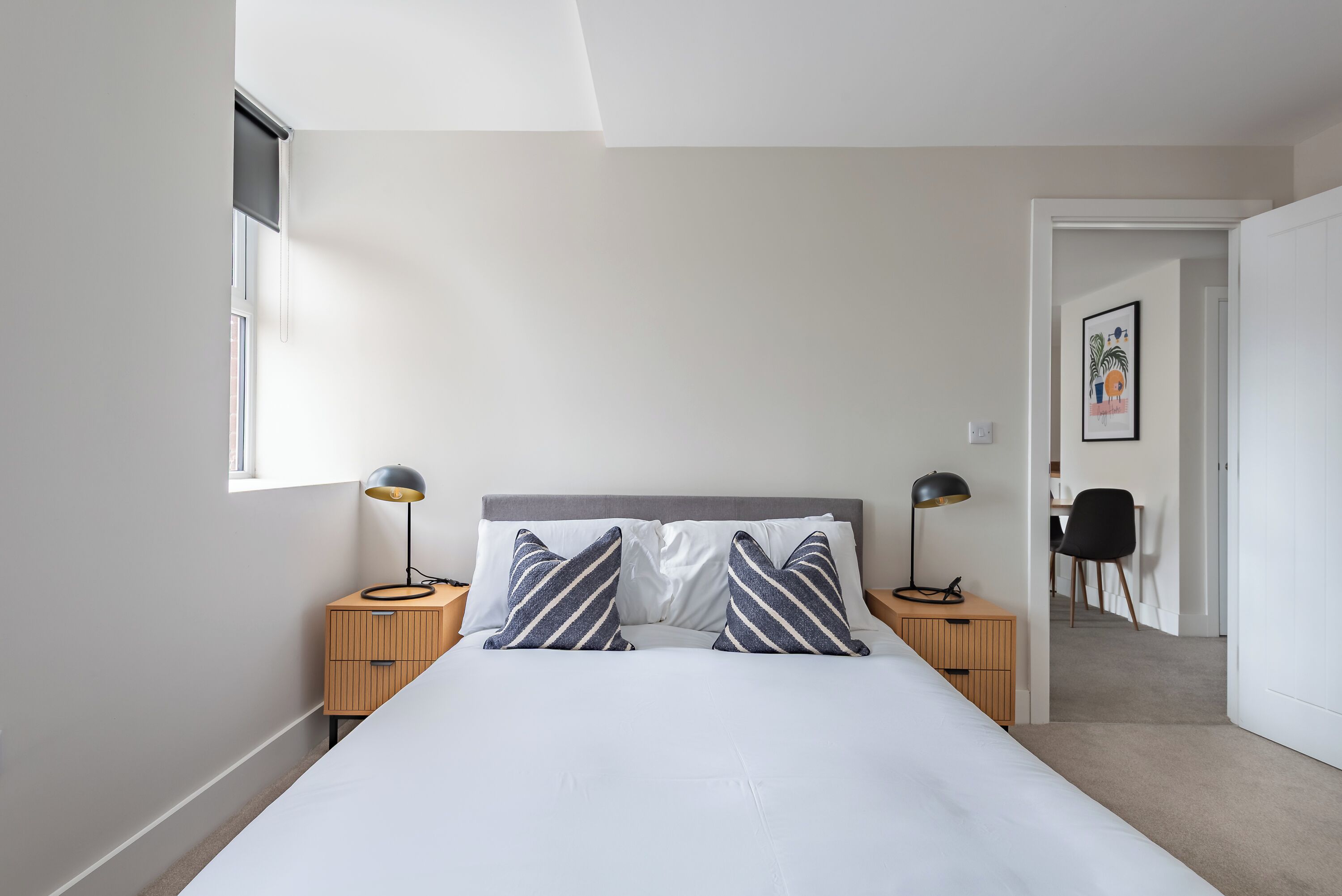 A bedroom with a bed, two bedside tables, a desk, and a chair.
