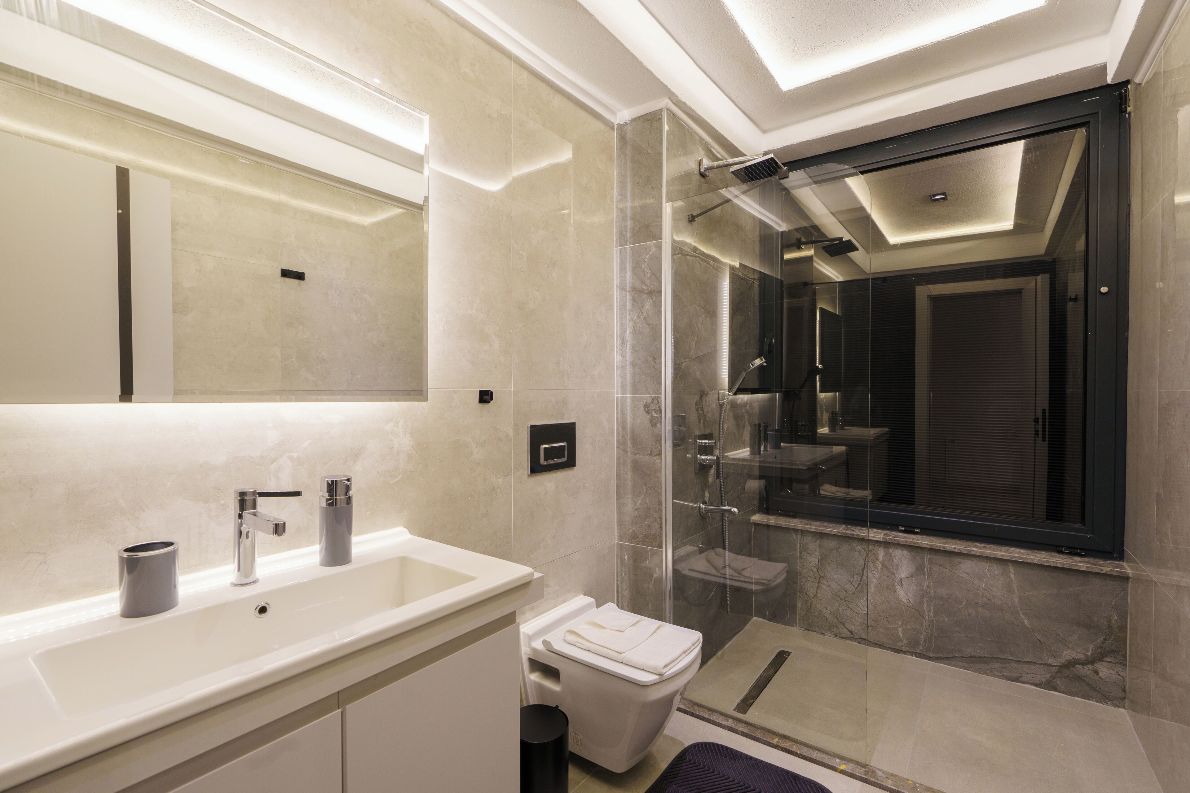 Une salle de bain moderne avec une douche à parois de verre, un lavabo blanc et un grand miroir.
