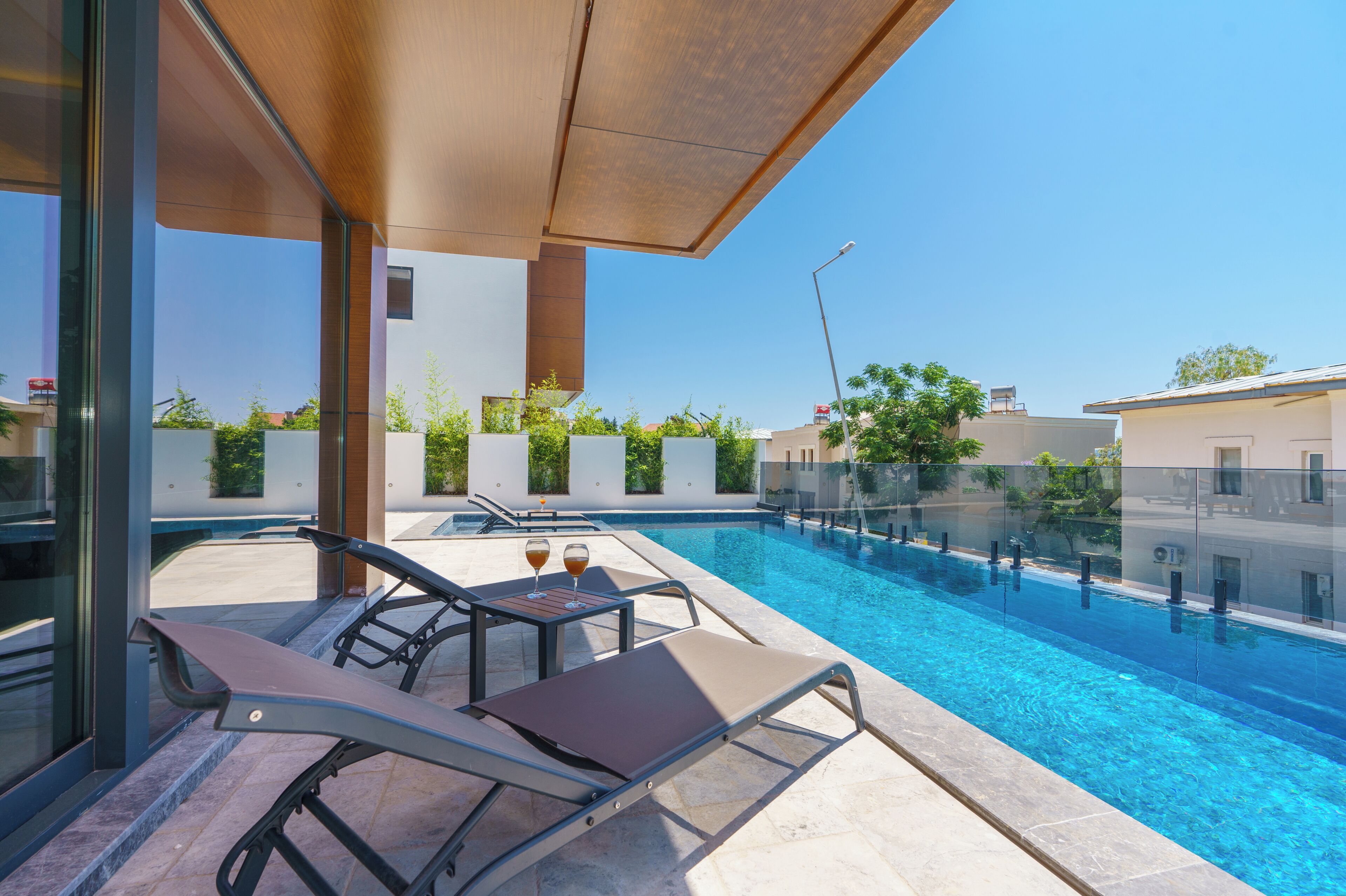 A modern outdoor pool area with lounge chairs and a glass railing.