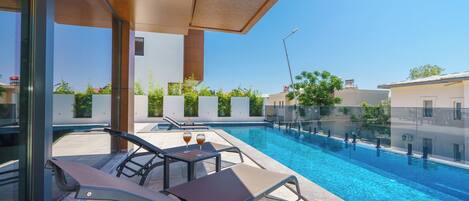 A modern outdoor pool area with lounge chairs and a glass railing.