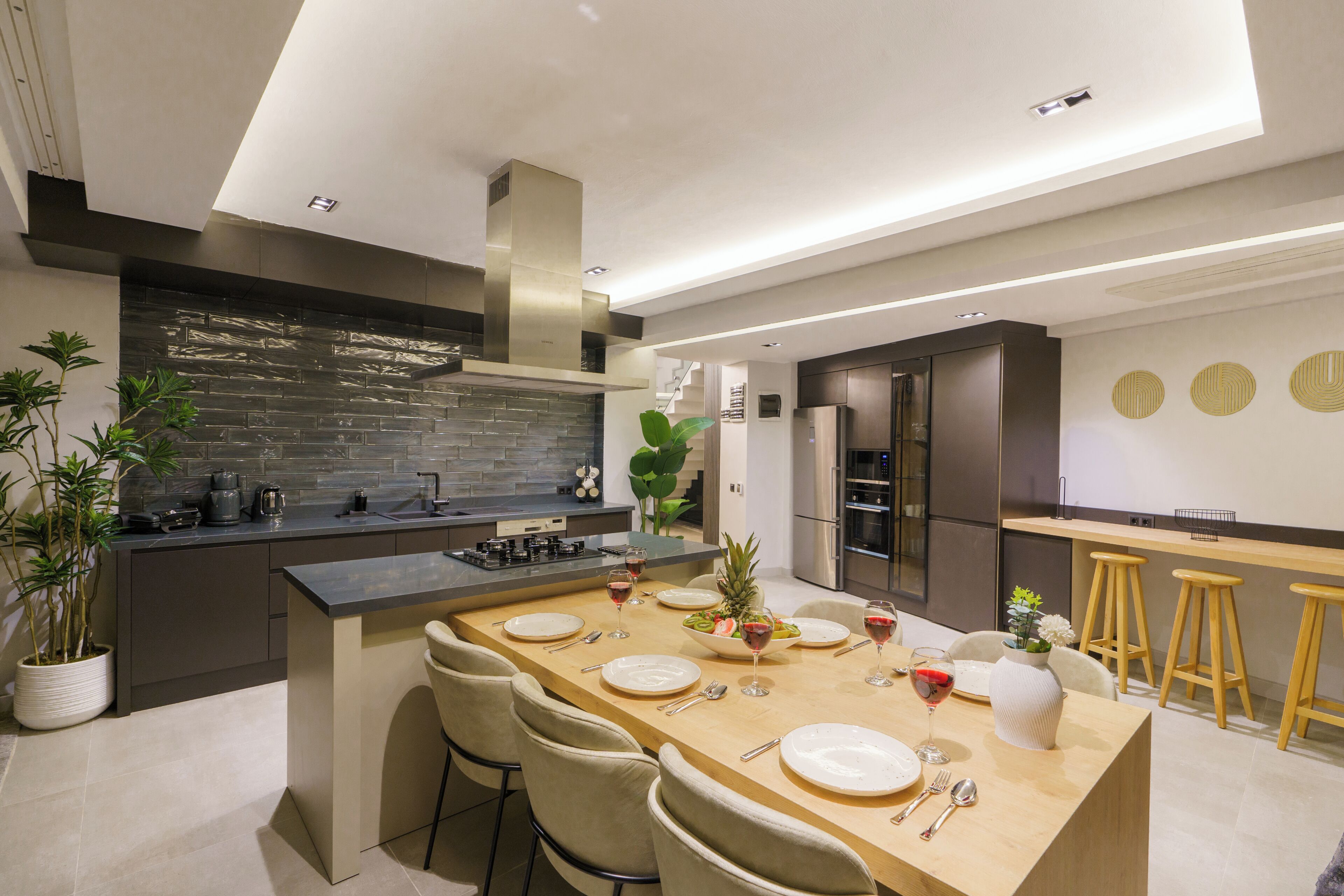 A modern kitchen with a central island, bar stools, and a dining area set for six.