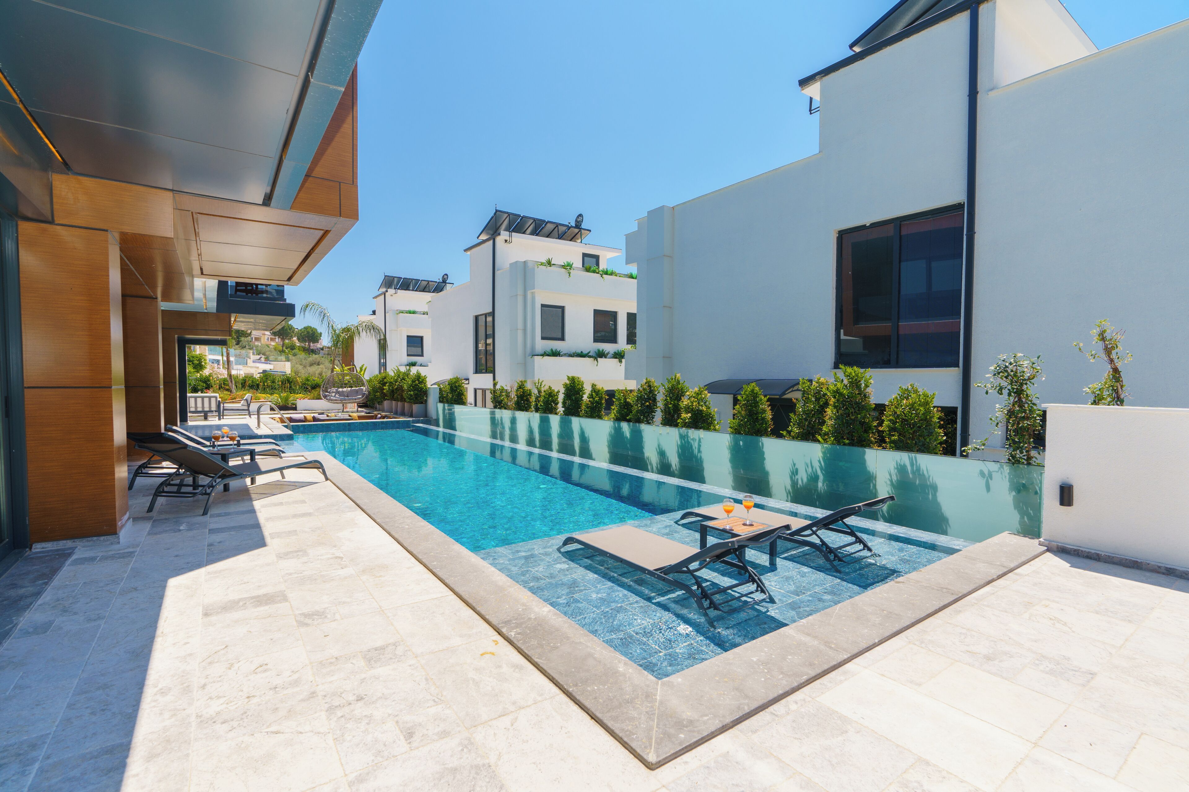 A modern outdoor pool area with lounge chairs and a clear blue pool.