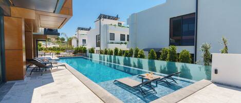A modern outdoor pool area with lounge chairs and a clear blue pool.