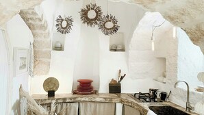 A rustic kitchen with a stone wall, a sink, and a stove. - Designer trullo in Valle d'Itria, Apulia (Cisternino)