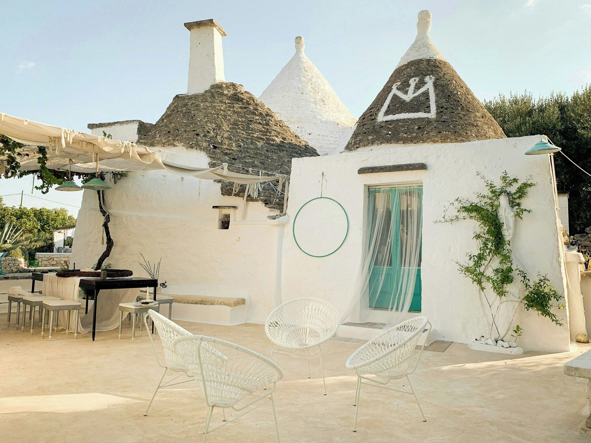 A white building with conical roofs, a circular window, and outdoor seating.