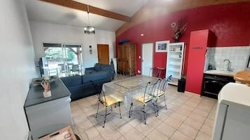 En rummelig opholdsstue med spisebord og stole, en sofa og et køkkenområde med en rød detaljevæg.