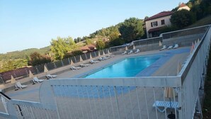 A swimming pool with a white fence, lounge chairs, and umbrellas. - Apartment*Residence with pool*Parking*3 min from downtown Sarlat (Sarlat-la-Canéda)