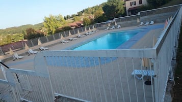 En swimmingpool med hvide hegn, liggestole og parasoller.