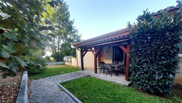 A patio area with a table and chairs, surrounded by a hedge and a small garden. - Apartment*Residence with pool*Parking*3 min from downtown Sarlat (Sarlat-la-Canéda)