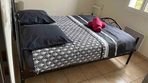 A single bed with a patterned bedspread, two pillows, and a red item on the bed. - Apartment*Residence with pool*Parking*3 min from downtown Sarlat (Sarlat-la-Canéda)