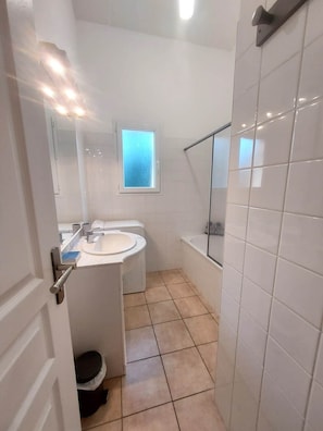 Une salle de bain avec un lavabo, un miroir, une fenêtre et une baignoire.