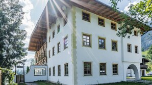 A multi-story building with a white facade, multiple windows, and a wooden roof. - Chalet in Piesendorf Near Kaprun Near Skiresort (Angerberg)