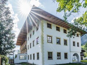 Ein mehrstöckiges Gebäude mit weißer Fassade, zahlreichen Fenstern und einem Holzdach.