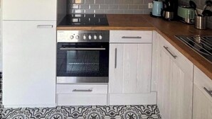 Una cocina con estufa, horno y salpicadero de baldosas grises.