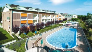 Et hotel med swimmingpool, udendørs siddepladser og en velplejet have.