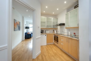 Een moderne keuken met houten kastjes, een ingebouwde oven en een vaatwasser.