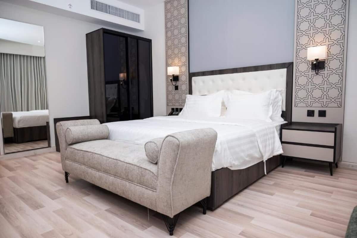 Ett modernt hotellrum med en stor säng, en soffa, en garderob och två sängbord med lampor.
