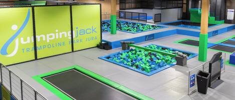 An indoor trampoline park with multiple trampolines and foam pits.