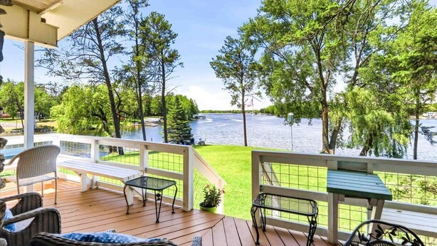 Terraza de madera con mobiliario exterior con vistas a un lago.