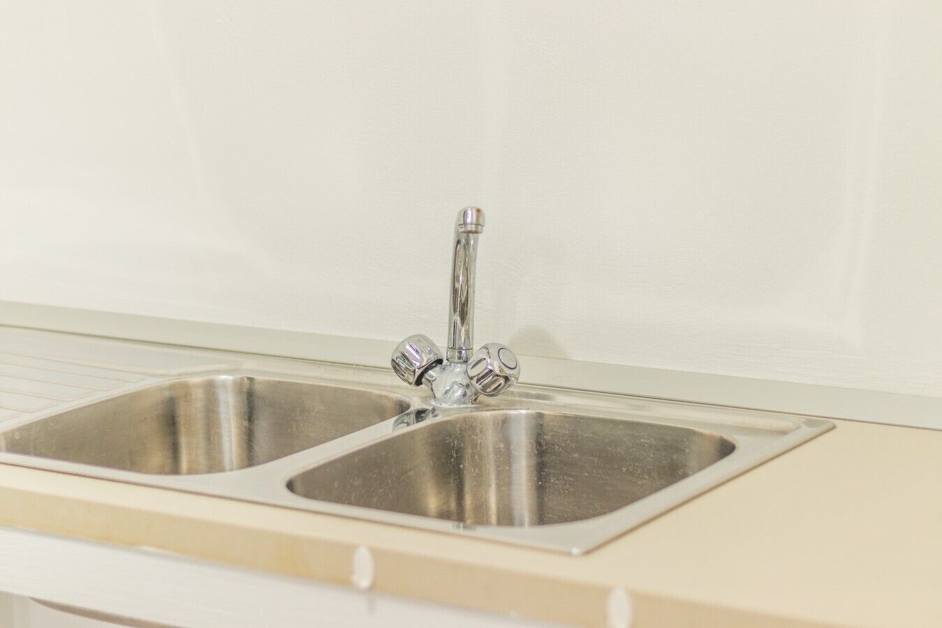 A kitchen with a double stainless steel sink and a beige countertop.