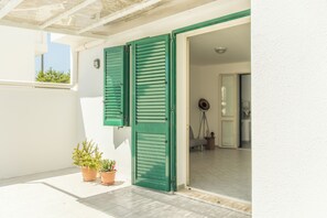 A balcony with a white wall, green shutters, and potted plants. - Simple House (Santa Maria di Leuca)