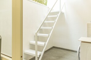 A white staircase leading to a landing, a small white counter, and a washing machine. - Simple House (Santa Maria di Leuca)