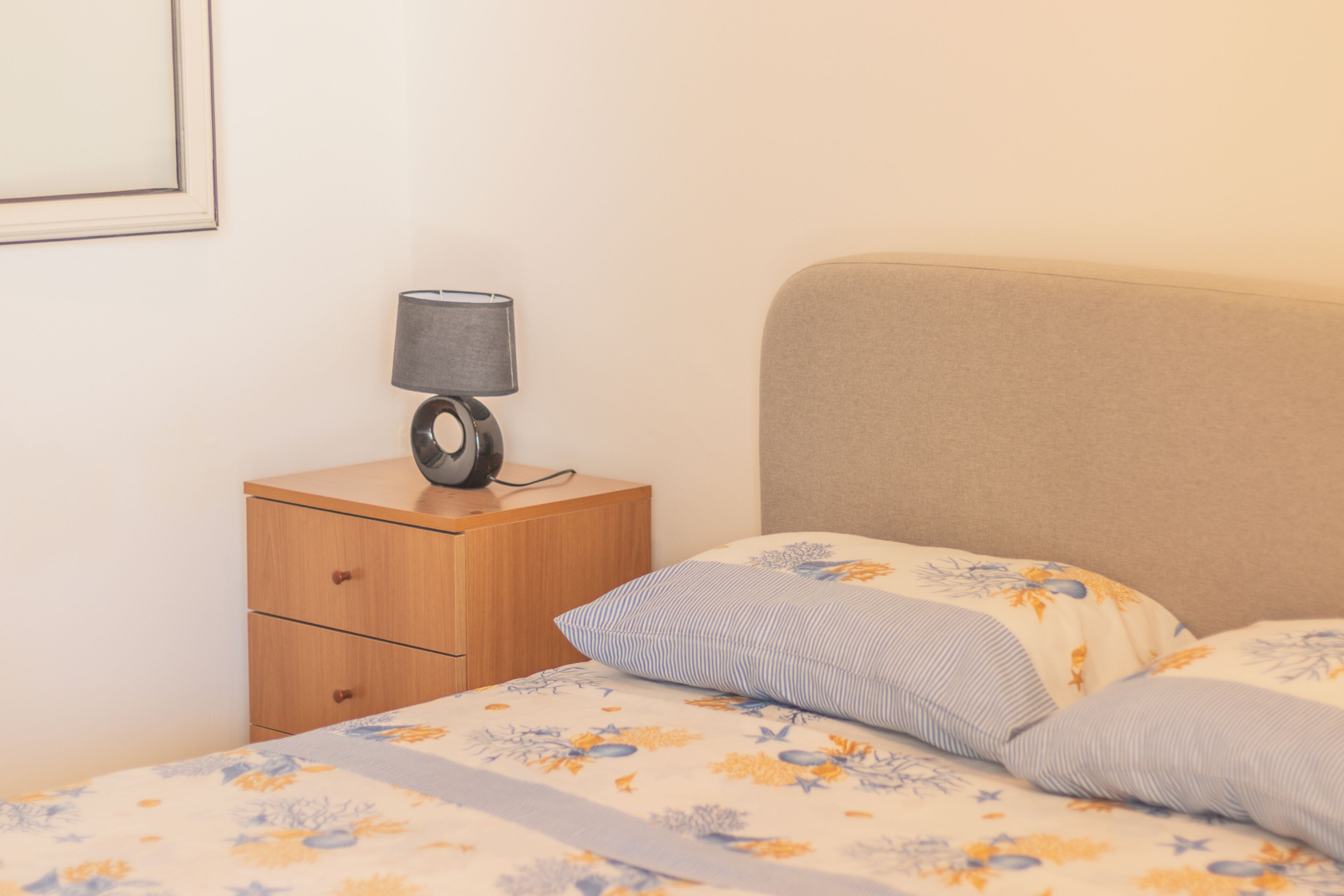 Une chambre à coucher avec un lit, une table de chevet avec une lampe et un tiroir.