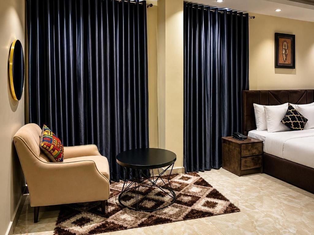 Een hotelkamer met een bed, een klein tafeltje, een bank en gordijnen.