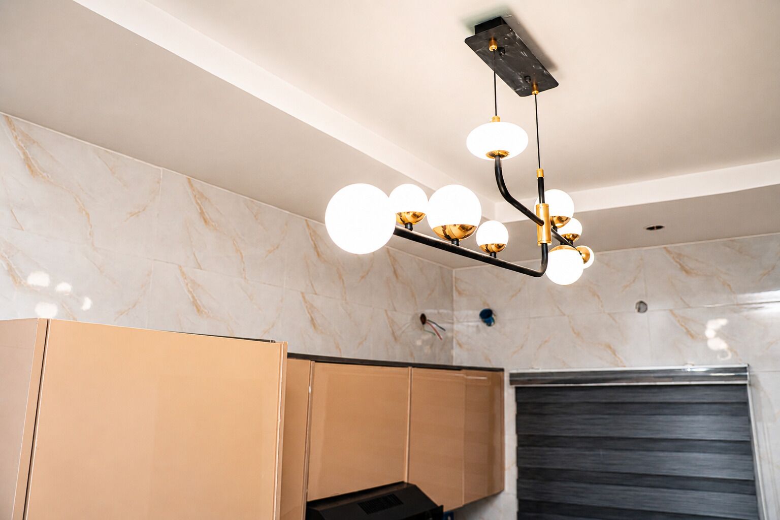 Ett modernt kök med väggar i marmor, ett svart tak och en unik lampa.