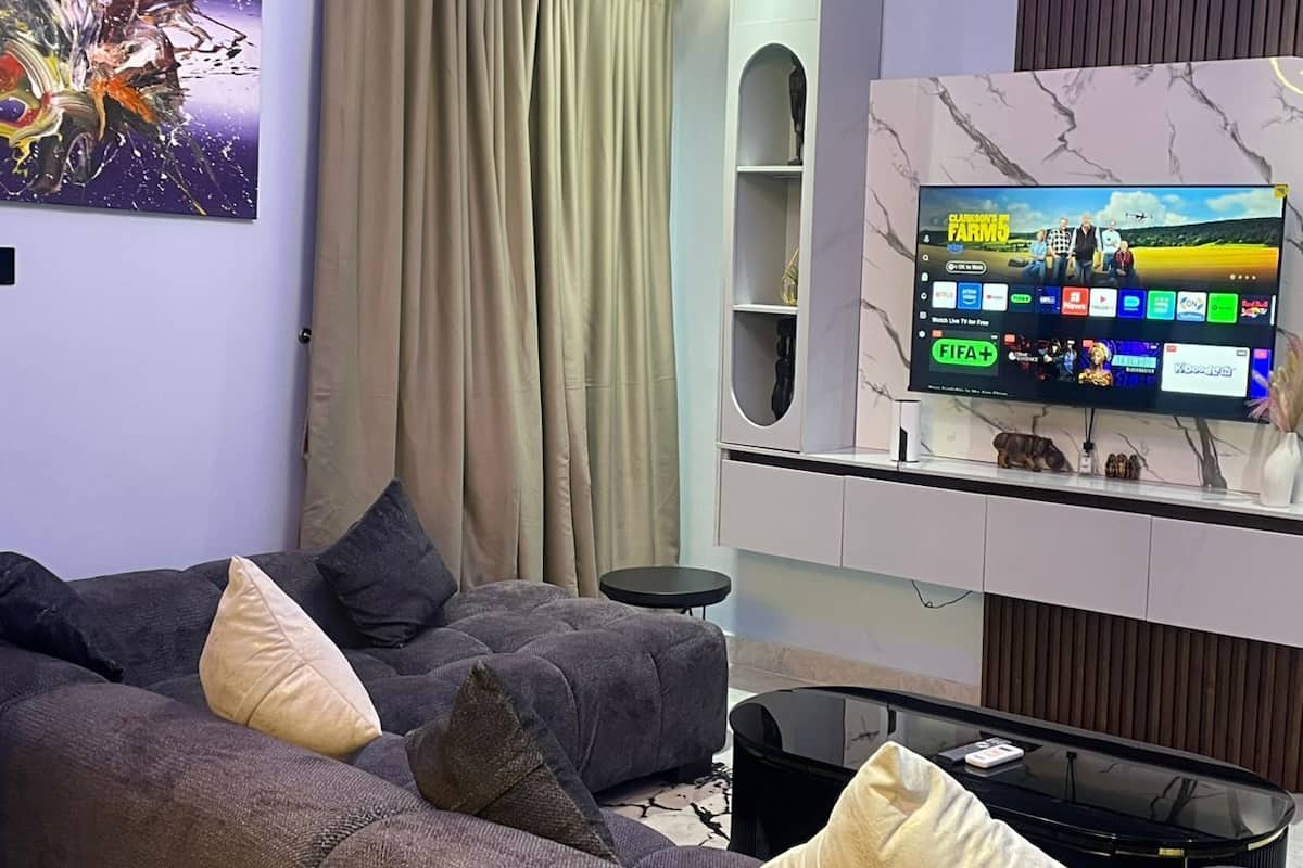 Una sala de estar moderna con un sofá seccional, un televisor de pantalla plana y una unidad de pared con diseño de mármol.