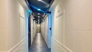 Un pasillo largo y estrecho en un hotel, con paredes blancas, piso oscuro e iluminación empotrada en el techo.