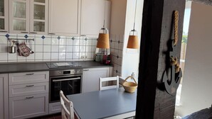 A kitchen with white cabinets, a stove, and a table with a basket. - "Sonneneck" - Garden view, half-timbered, 37 m², sleeps 2, dogs welcome (Bösdorf)
