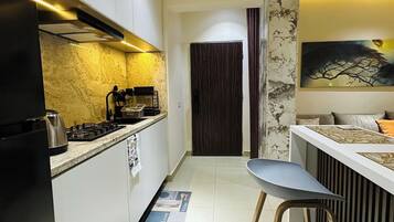 Een moderne keuken met een centraal eiland, een zithoek met een bar en een donker houten deur naar een andere kamer.