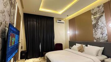 Een moderne hotelkamer met een groot bed, een flatscreen televisie, een airconditioning en een plafondlamp.