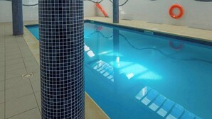 Ein Hallenbad mit gefliesten Wänden, einer klaren Decke und Sicherheitsringen.