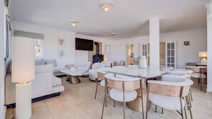 A modern living room with a round dining table, white sofas, and a fireplace. - 143 - Spacious Villa with Private Pool & Stunning Views (Fuengirola)
