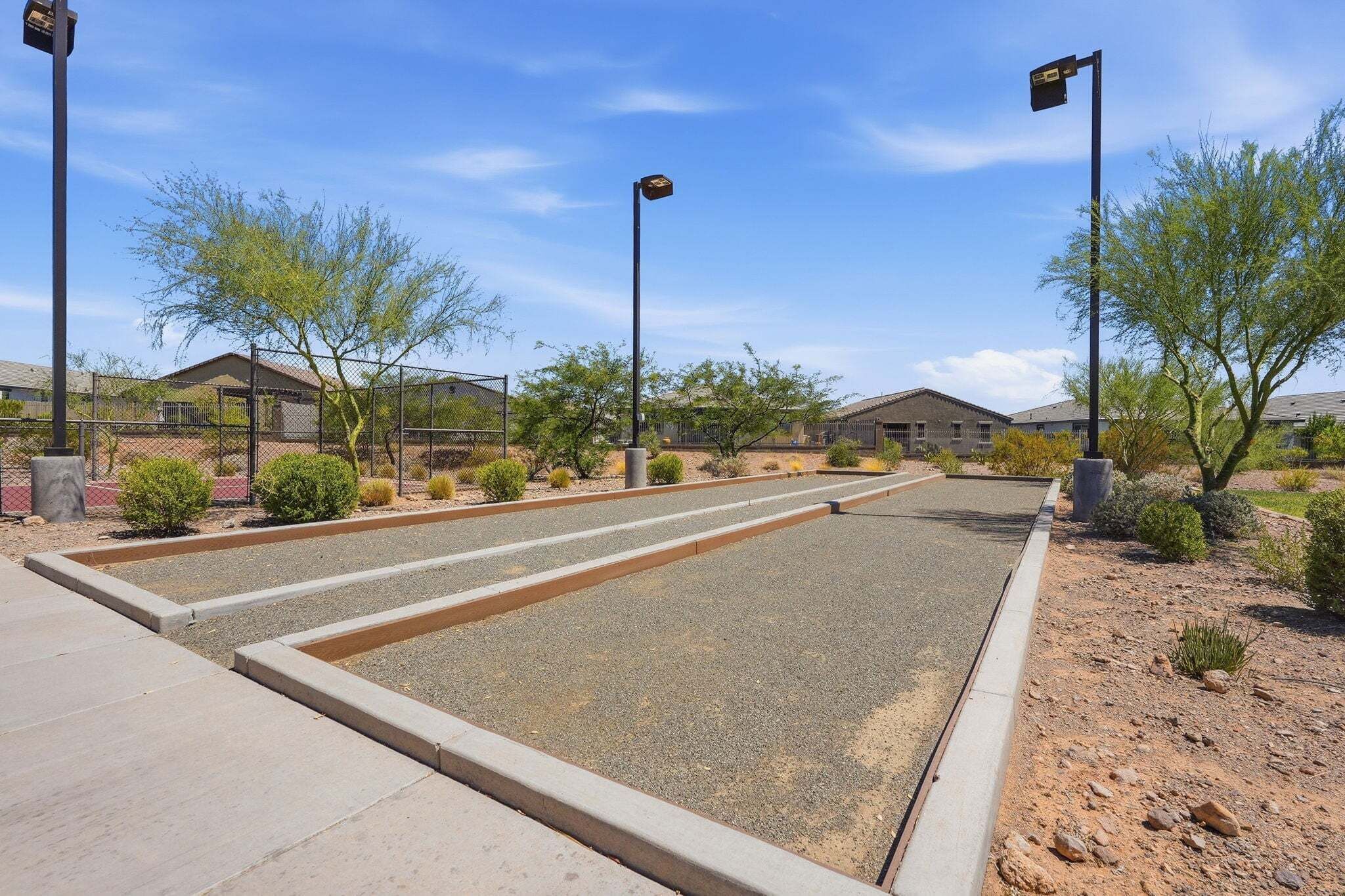 A parking lot with a clear sky, surrounded by buildings and sparse vegetation.