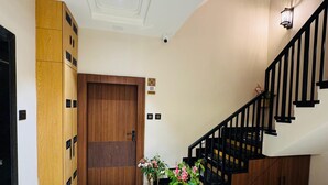 Un interior moderno con una puerta de madera, una escalera con barandillas negras y un suelo con diseño.