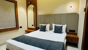 Un dormitorio moderno con una cama grande, cabecera de madera, mesita de noche y ventilador de techo.