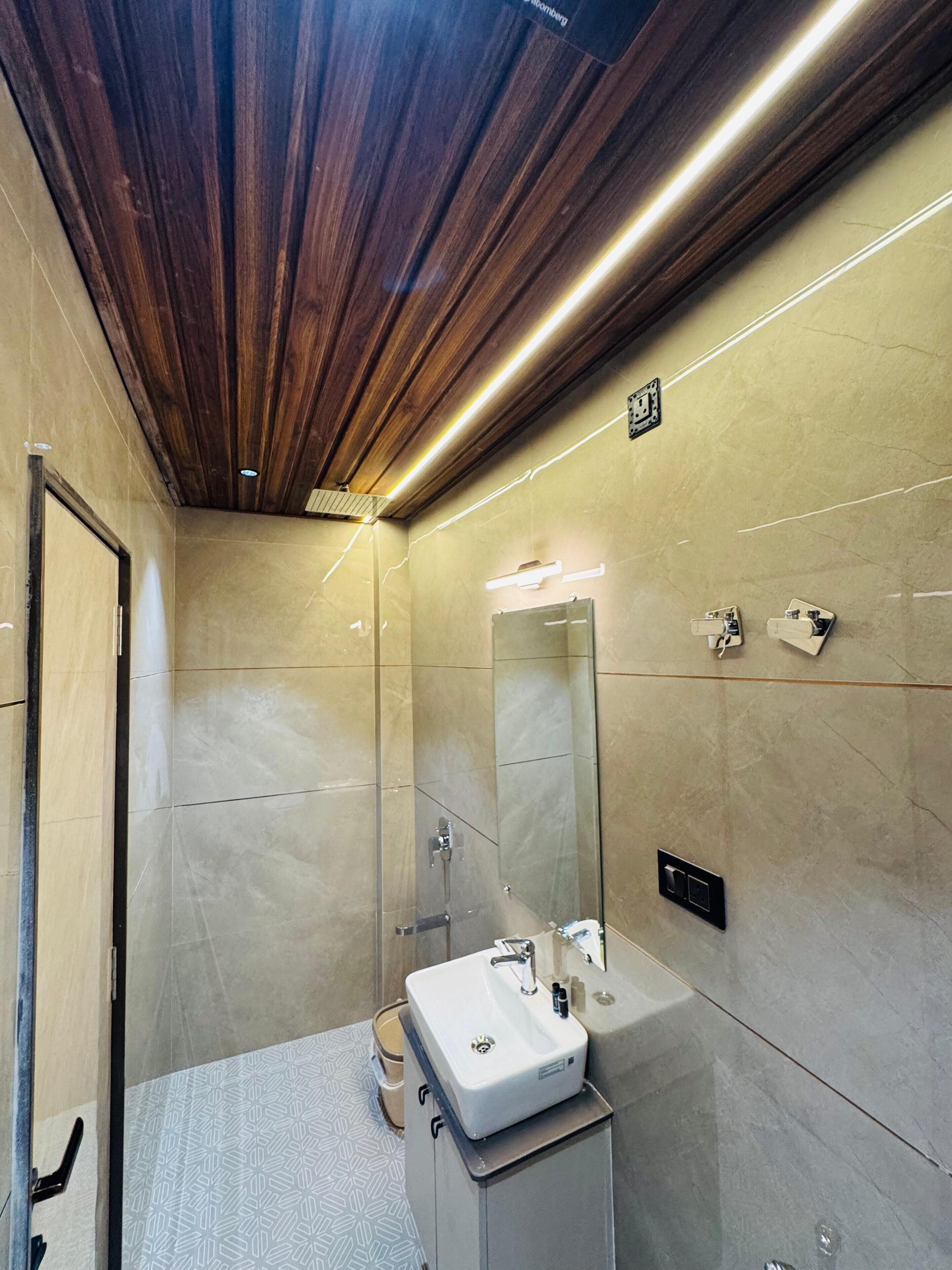 Un baño moderno con techo de madera, un espejo grande, un lavabo y una ducha.