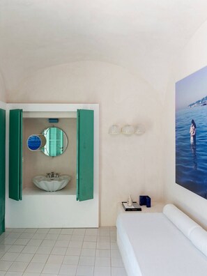 A bedroom with a bed, a bathroom with a sink and mirror, and a wall-mounted light fixture. - Villa Eletta, Capri (Marina Grande)