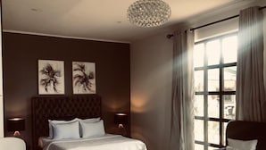 Un dormitorio con una cama grande, una mesita de centro redonda, una silla, un sofá y una ventana con cortinas.
