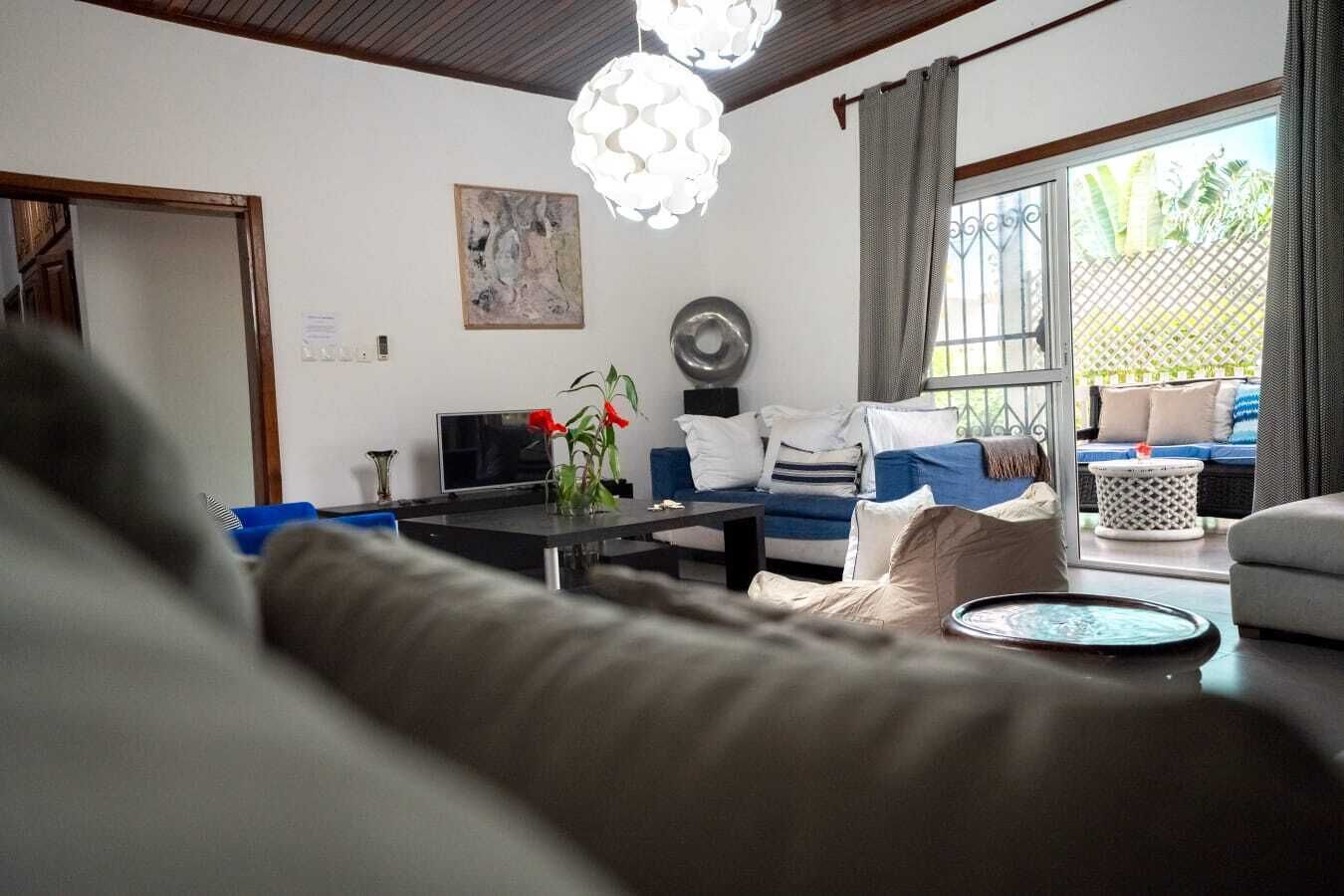 A living room with a sofa, a coffee table, a TV, and a dining table.