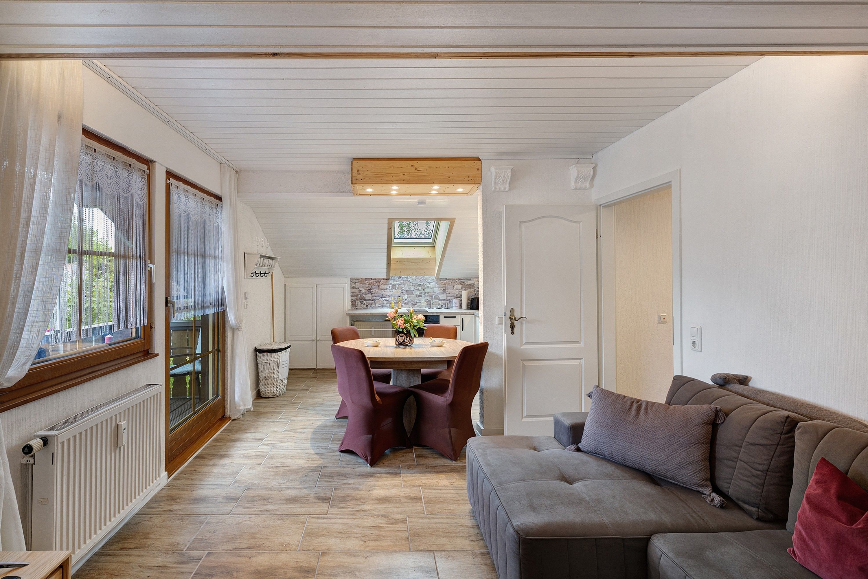 Ein gemütliches Interieur mit Essbereich, einer Couch und einer Küche im Hintergrund.