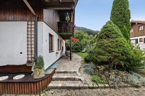 A narrow stone pathway leading to a wooden bench with a view of a mountain.
