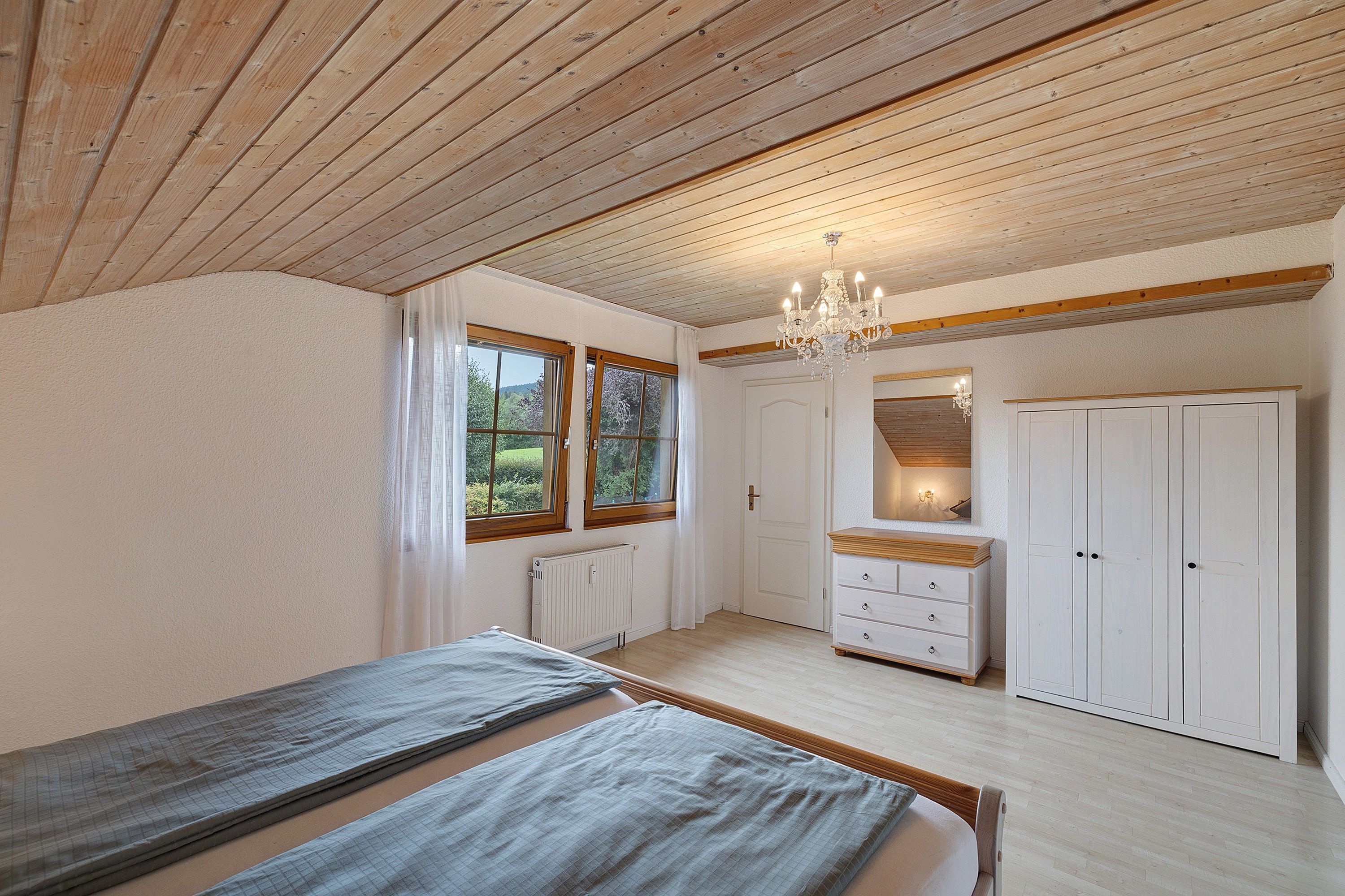Un dormitorio con cama, cómoda, espejo y candelabro.