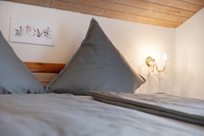 Une chambre à coucher avec une tête de lit en bois, un luminaire fixé au mur et une œuvre d’art encadrée.