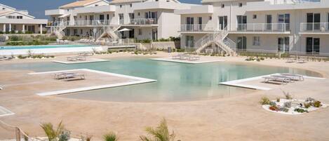 A resort with multiple buildings, a central pool, and outdoor seating areas.