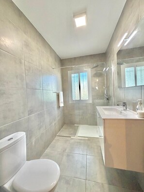 Un baño moderno con inodoro, ducha y lavamanos.