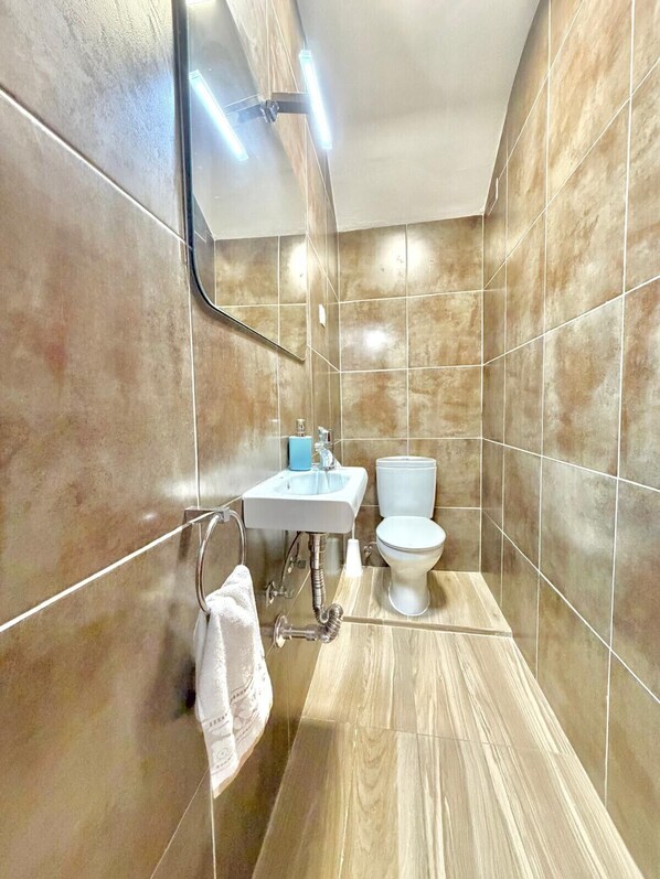 Un baño con lavamanos, inodoro y perchero para toallas.